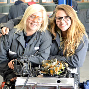 Sparta seniors and Automotive Technology students Alyssa Graham (right) and Tiffany Tasma lean on a diesel engine