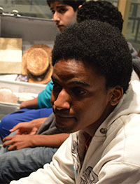 Freshman Waicel Jose Reyes sits by a suitcase packed by an immigrant in the museum’s exhibit