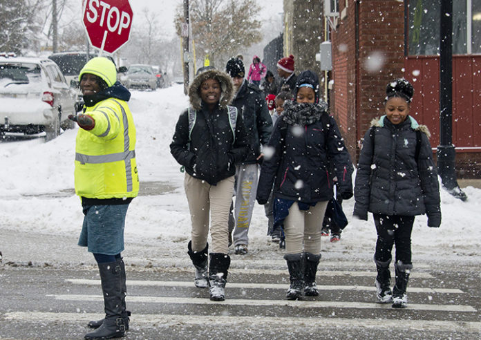 KattieEason9 Kattie Eason makes sure all traffic has stopped on Wealthy Street to make way for eighth-graders (from left) Sharkia Caldwell, Zaionna Love and Kalyce Russell