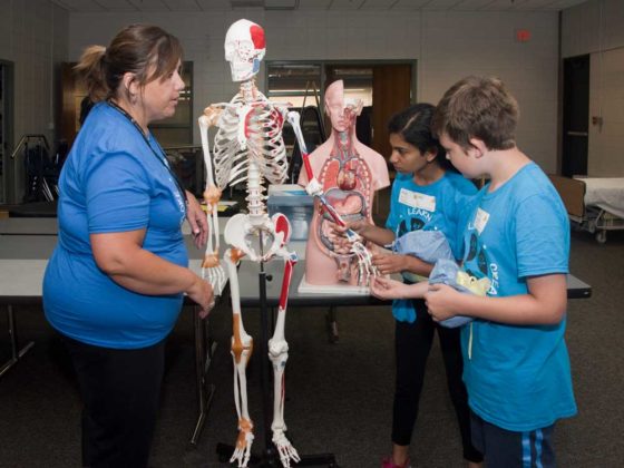 Nurse and instructor Jen Gebhardt teaches Shreya Anil, eighth grade, Forest HIlls Northern Hills Middle; and Rhone Spink-Knight, seventh grade, EGR Middle; about the skeleton