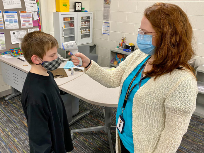 Nurses administering COVID tests at school, working with families